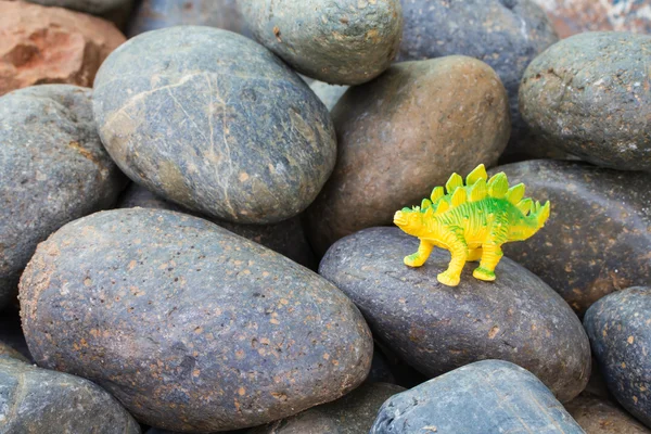 Dinosaurio plástico en piedra de guijarro — Foto de Stock