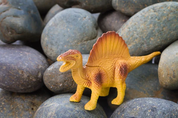 Dinosaure en plastique sur fond de pierre de galets — Photo