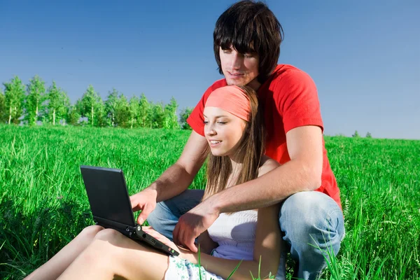 Ragazza dai capelli lunghi con taccuino e con ragazzo sull'erba Foto Stock