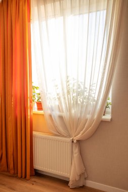 Beautiful translucent orange and white curtains with drapery in an apartment