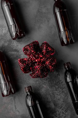 Dilimlenmiş nar meyvesi ve arka planda egzotik içeceklerle dolu bir sürü şişe.