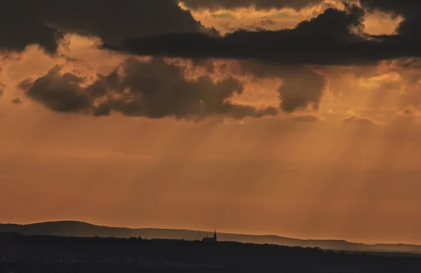 Piccola sagoma di una chiesa di campagna sullo sfondo contro il cielo arancione al tramonto — Foto Stock