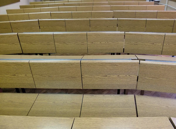 Фрагмент лекционного зала с пустыми рядами деревянных столов — стоковое фото