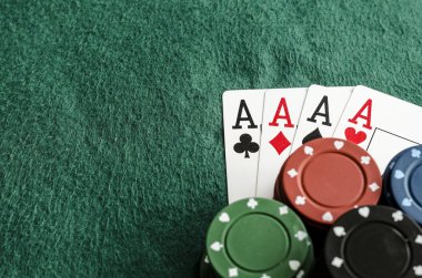 Dört as yeşil masa örtüsü üzerinde casino fişleri ile