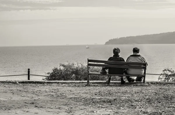 Casal velho sentado no banco observando o oceano — Fotografia de Stock