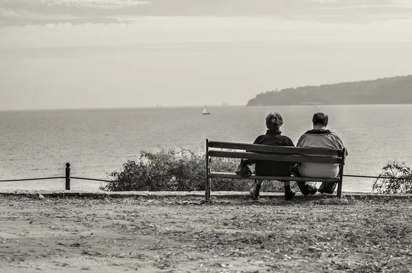 Gamla paret sitter på bänken tittar på havet Royaltyfria Stockfoton