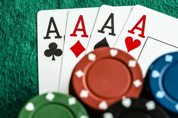 Vier Asse mit Casino-Chips auf grünem Tischtuch lizenzfreie Stockbilder