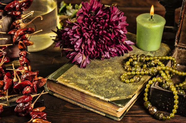 eski kitap, çiçek, mum ve yeşil kolye natürmort, karanlık grunge ışık Rönesans konseptiyle birlikte açık mücevher kutusu