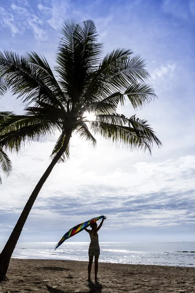 Dziewczyna na tropikalnej plaży trzymając kolorowe kawałek tkaniny — Zdjęcie stockowe
