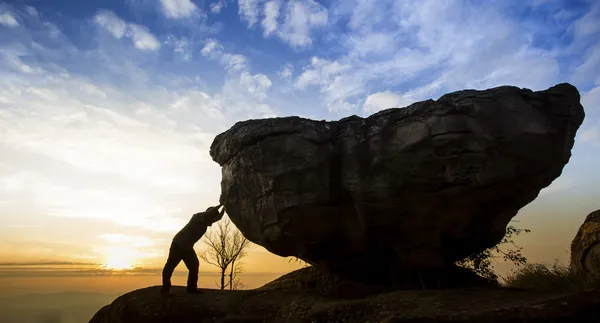 Uomo che spinge un masso su una roccia — Foto Stock