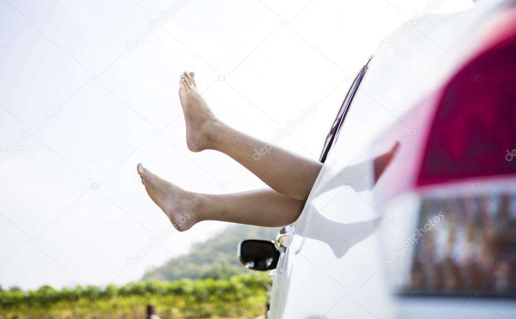 Woman legs out the windows in car above the clouds