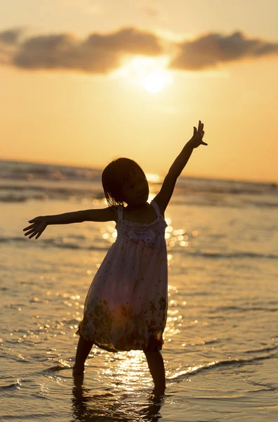 Glad tjej står på stranden på dawn tiden — Stockfoto