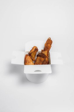 Yağda kızartılmış tavuk budu ve ekmek kırıntıları beyaz arka planda beyaz bir kutunun içinde, üst tarafta.