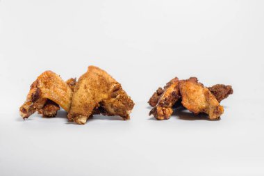 Yağda kızartılmış tavuk kanatları ve ekmek kırıntıları beyaz arka planda üç parçaya ayrılmıştır.