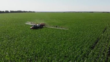 Bir traktör püskürtücü tarlaya mısır püskürtür. 4K İHA 'dan ateş ediliyor. Tarımsal bir alana kimyasal gübre serpmek