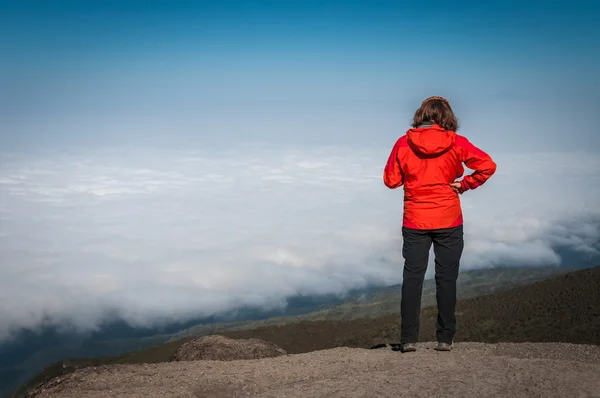 Lady in Red gazing out over clouds above Africa — Stock Photo, Image