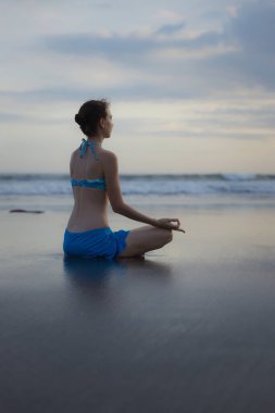 Bali 'de plaj yogası. Lotus pozu. Padmasana. Eller Gyan Mudra 'da. Meditasyon ve konsantrasyon. Zen hayatı. Bedensel ve zihinsel rahatlama. Yoga inzivası. Arkadan bak. Uzayı kopyala Gün batımı zamanı.