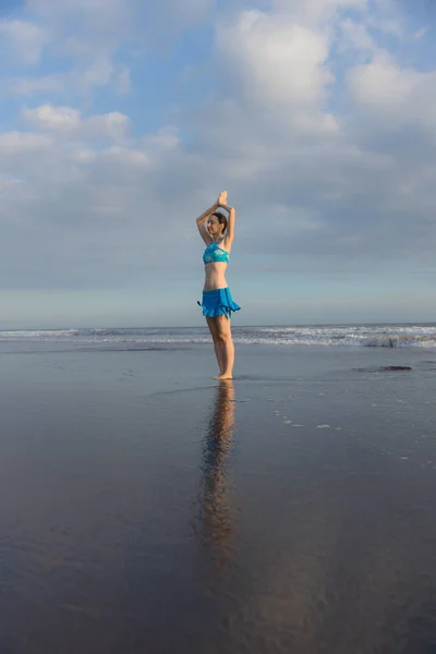 ヨガポーズ Vrikshasana Asana 日没時に海の近くのビーチで木のポーズを練習している若い女性 ナマストムドラで腕を上げる 水の反射 ヨガの練習をOutdoot コピースペース バリ島 — ストック写真