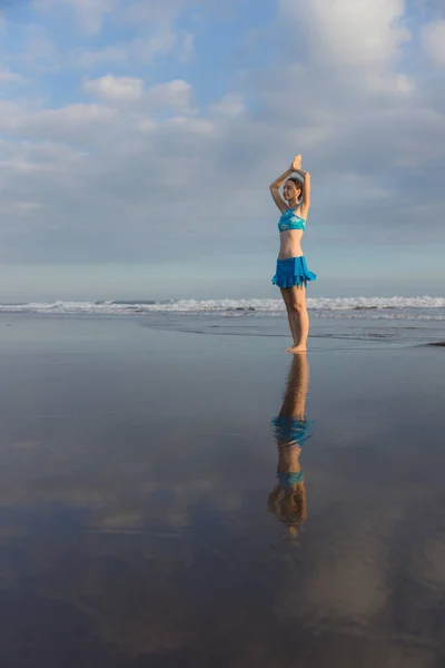 ヨガポーズ Vrikshasana Asana 日没時に海の近くのビーチで木のポーズを練習している若い女性 ナマストムドラで腕を上げる 水の反射 ヨガの練習をOutdoot コピースペース バリ島 — ストック写真