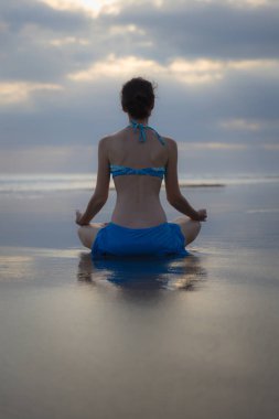 Bali 'de günbatımı plaj yoga antrenmanı. Lotus pozu. Padmasana. Eller Gyan Mudra 'da. Meditasyon ve konsantrasyon. Zen hayatı. Bedensel ve zihinsel rahatlama. Yoga inzivası. Arkadan bak. Boşluğu kopyala.