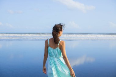 Sahildeki güzel beyaz kadının arka plan portresi. Asya 'da yaz tatili. Elbise giyen genç bir kadın. Güneşli bir gün. Mavi gökyüzü. Ufuk çizgisi olan okyanus. Seyahat yaşam tarzı. Bali Endonezya