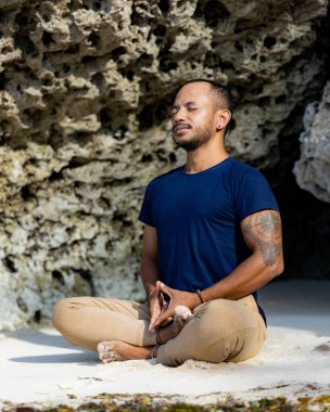 Sahilde meditasyon ve yoga. Lotus pozunda kumda oturan Asyalı adam. Padmasana. Eller Jupiter 'de Mudra' ya kilitlendi. Kapalı gözler. Yoga inzivası. Sağlıklı bir yaşam tarzı. Thomas Sahili, Bali, Endonezya