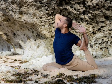 Çekici Asyalı adam Eka Pada Rajakapotasana, Tek Ayaklı Kral Güvercin Pozu çalışıyor. Göğüs açıcı nefes almakta güçlük çekiyor. Sağlıklı bir yaşam tarzı. Esnek vücut. Yoga inzivası. Thomas Sahili, Bali, Endonezya