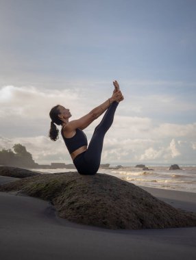 Açık havada yoga pratiği. İnce Asyalı kadın Ubhaya Padangusthasana, Geniş Açı Ön Kıvrımlı. Bacaklarını ve çekirdeğini güçlendir. Kişisel bakım konsepti. Yoga inzivası. Mengening Plajı, Bali, Endonezya