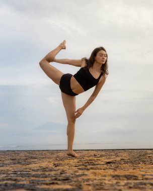 Gün doğumu yogası ve esneme. Çekici beyaz kadın yoga yapıyor, Natarajasana 'da duruyor, Dans Pozu Lordu. Dengede duruyor, Asana 'yı büküyor. Kumsalda egzersiz. Bali, Endonezya