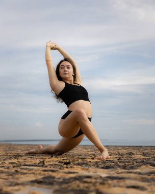 Sabahları esneme egzersizi. Sportif ve atletik genç bayan sahilde ısınıyor. Fitness, spor, sağlık konsepti. Sağlıklı bir yaşam tarzı. Aktif kadın egzersizleri. Uzayı kopyala Bali, Endonezya