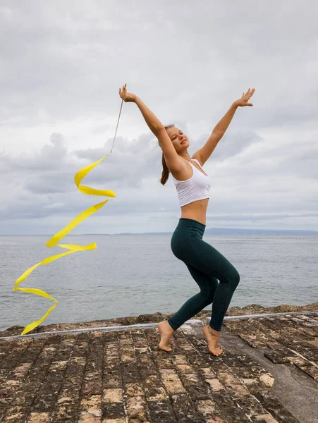 Mladá Profesionální Gymnastka Tančící Žlutou Stuhou Venkovní Tělocvik Zatažené Pozadí — Stock fotografie