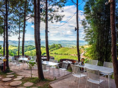 Kafe tarzında güzel bir manzara. Masaları ve sandalyeleri dışarıda dağ manzarasına karşı..
