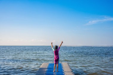 Kızı, deniz rıhtımındaki Plastik Liman 'da yalınayak yürümekten mutlu..