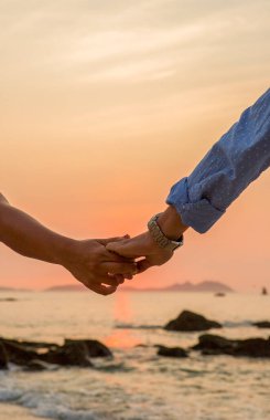 Çiftler el ele tutuşup gün batımını izliyor.