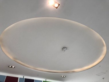 Perakende mağazasının merkezinde dolaylı ışıklandırmalı koyları olan yuvarlak ya da yuvarlak alçı taşı sahte tavanı