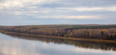 Ormanların arasında güzel, geniş bir nehir sonbaharı. Sonbahar renkleriyle sakin ve sessiz bir yer. Nehir adasının ortasında. Yukarıdan uzaklığa görüntüle