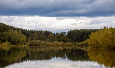Güzel bir sonbahar gününde sakin gölet suyunda renkli yapraklar yansıyor. Dinlenmek için sessiz ve güzel bir yer..