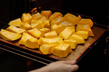 Fırında kabak dilimleri fırında pişiyor. Ev yapımı yemekler, vejetaryen yemekleri, sağlıklı yiyecekler, turuncu sebzeler, fırın tepsisi ve peçete, fırında pişmiş sebzeler, pop sanat, diyet sırasında tatlı.