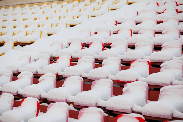 Kunststoffsitze in einer Reihe im Stadion sind mit Schnee bedeckt. — Stockfoto