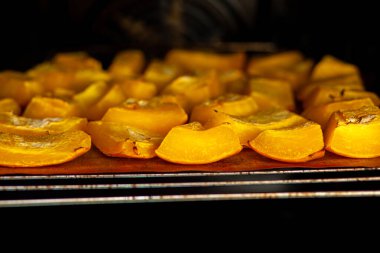 Fırında kabak dilimleri fırında pişiyor. Ev yapımı yemekler, vejetaryen yemekleri, sağlıklı yiyecekler, turuncu sebzeler, fırın tepsisi ve peçete, fırında pişmiş sebzeler, pop sanat, diyet sırasında tatlı.