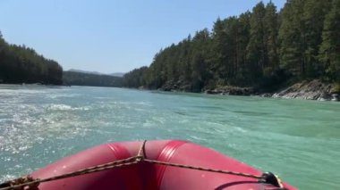 Dağ nehrindeki bir motorlu teknede akıntıya karşı hareket. Hızlı akan geniş ve tamamen akan bir dağ nehri. Büyük kayalar sudan dışarı çıkar. Büyük Dağ Nehri Katun, Altai Cumhuriyeti.