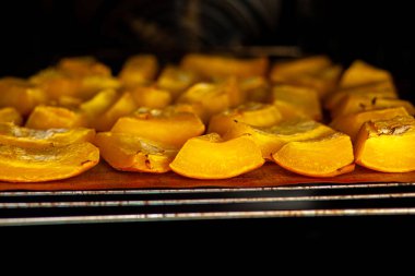 Fırında kabak dilimleri fırında pişiyor. Ev yapımı yemekler, vejetaryen yemekleri, sağlıklı yiyecekler, turuncu sebzeler, fırın tepsisi ve peçete, fırında pişmiş sebzeler, pop sanat, diyet sırasında tatlı.