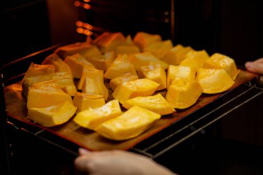 Fırında kabak dilimleri fırında pişiyor. Ev yapımı yemekler, vejetaryen yemekleri, sağlıklı yiyecekler, turuncu sebzeler, fırın tepsisi ve peçete, fırında pişmiş sebzeler, pop sanat, diyet sırasında tatlı.