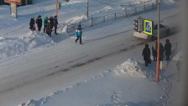 ロシアのケメロヴォ 2021年11月26日 人々は雲の多い曇りの天候で横断歩道上の信号で冬には街の道路を横断します 車の歩行者を渡すことを停止 — ストック動画