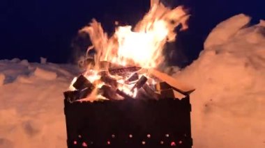 Izgaraya istiflenmiş odun geceleri iyi ve parlak yanar. Kışın geceleri dışarıda pişirmek için odun yakıyorum. Kızarmış et ve ateşte barbekü. Ateşten ısınalım..