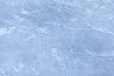 Açık hava seansından sonra buz pateni izleri olan boş bir buz pisti. Gün ışığında buz pateni pisti dokusu karla kaplı. Mavi buz pateni pistini kapatın, boşluğu kopyalayın