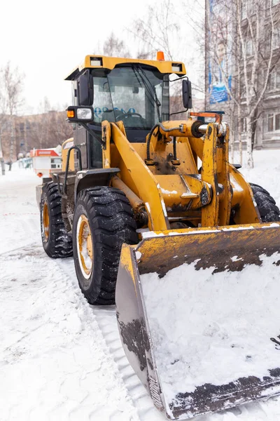大橙色拖拉机把路上的雪清理干净 然后装上卡车 冬季从雪地中清理和清洁城市的道路 降雪和暴风雪后的除雪 — 图库照片
