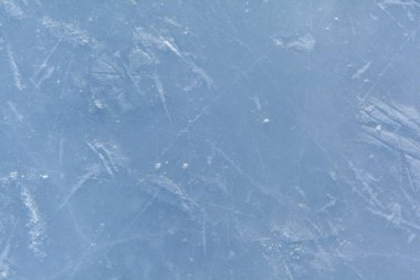 Açık hava seansından sonra buz pateni izleri olan boş bir buz pisti. Gün ışığında buz pateni pisti dokusu karla kaplı. Mavi buz pateni pistini kapatın, boşluğu kopyalayın