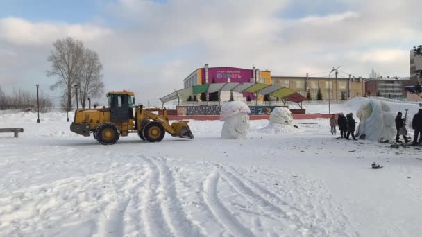 2022年2月16日 俄罗斯克麦罗沃地区 新年过后 一辆黄色拖拉机在圣诞树旁的城市广场上拆除了雪雕 冬季除雪 — 图库视频影像