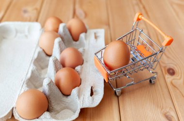 Karton torbanın yanındaki alışveriş sepetinde birkaç tavuk yumurtası değerli bir besleyici ürün olarak bir tavuk yumurtası kırılgan yumurtaları taşımak ve depolamak için bir tepsi. Yumurta paketi, önemli bir yiyecek.